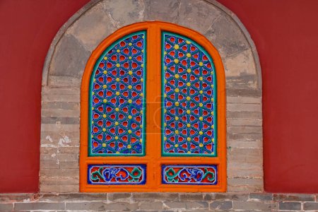 Photo for Red facade and colorfully painted bricked up symmetrical window at the Priests' House in Kumbum Tibetan Monastery, Xining, China - Royalty Free Image