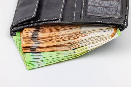 A black purse is overflowing with euro banknotes and banknotes