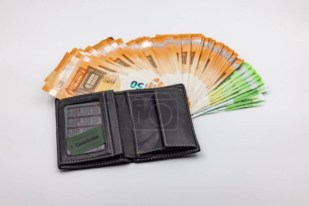 Téléchargez les photos : Wealth in a purse with a fan of euro banknotes against a white background in the studio - en image libre de droit