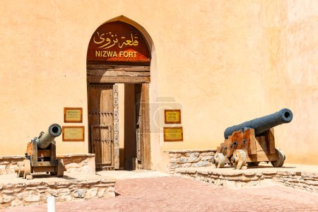 Photo for The facade of the fortress of Nizwa with wooden door and cannons, Nizwa, Oman - Royalty Free Image