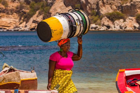 Téléchargez les photos : Une femme porte des cuves vides sans effort sur sa tête, île Santiago, îles du Cap-Vert dans l'océan Atlantique - en image libre de droit