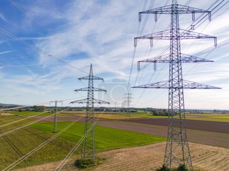 Vista aérea de una fila de pilones de alto voltaje con muchas líneas eléctricas en el área rural hasta el horizonte