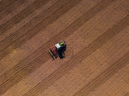 Photo for A tractor with plow on a field plowing from the ground directly from above with drone - Royalty Free Image