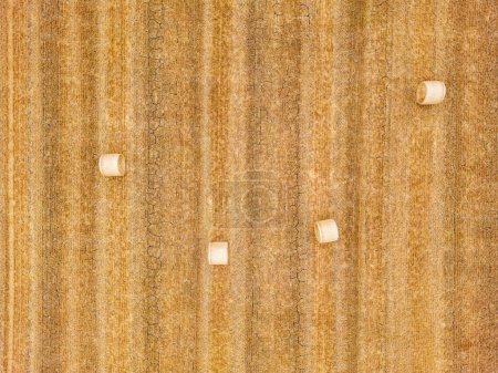Aerial view of four hay bales on a dry stubble field with cracks in the ground, Hesse, Germany