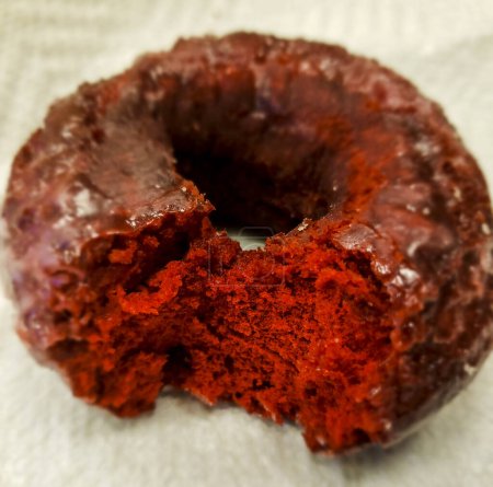 Blick auf einen teilweise verzehrten Donut aus rotem Samt, der auf einer Papierserviette sitzt