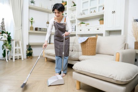 Foto de Feliz asiática joven mujer barrer el suelo a la limpieza de la casa, estilo de vida saludable concepto - Imagen libre de derechos