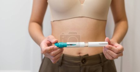 Close up woman using IVF treatment injection on belly to prepare reproductive fertility , Ovulation stimulation . 