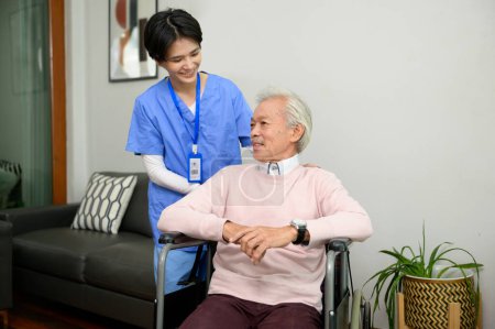 Eine asiatische Krankenschwester kümmert sich im Seniorenzentrum um einen älteren Mann, der im Rollstuhl sitzt.