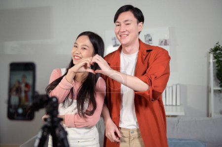 Photo for Asian young couple tiktokers are making video dancing  via smartphone together,  share video content on social media. - Royalty Free Image