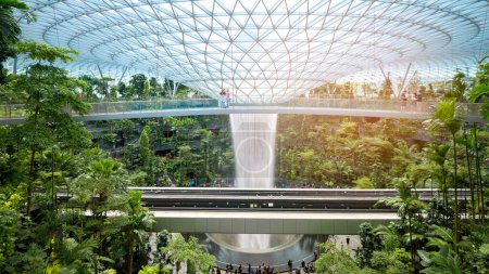 Foto de Changi, Singapore - 26/12/2022 : Jewel Changi Airport , artificial waterfall dome with plants where is most famous eco landmark combined with shopping mall in Changi Airport . - Imagen libre de derechos
