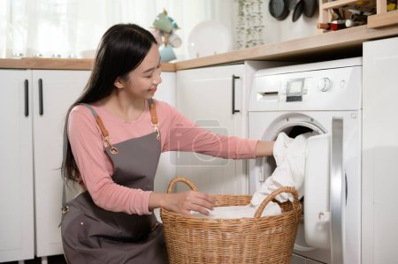 Téléchargez les photos : Heureuse jeune femme asiatique fait la lessive à la maison, concept de mode de vie sain - en image libre de droit