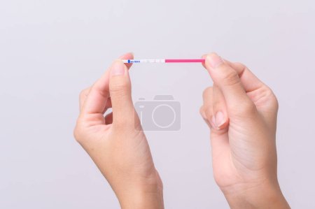 Téléchargez les photos : Gros plan femme utilisant le test d'ovulation (LH) ou (test de grossesse HCG) sur fond blanc - en image libre de droit