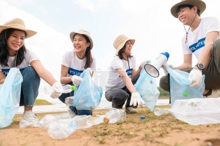 Foto de Voluntarios de la comunidad juvenil asiática usando bolsas de basura limpiando la naturaleza par - Imagen libre de derechos