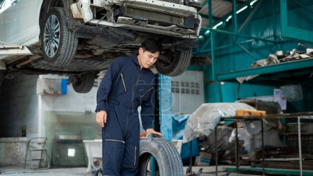 Téléchargez les photos : Mécanicien automobile travaillant dans le garage changer de roues. concept de service de réparation et d'entretien automobile. - en image libre de droit