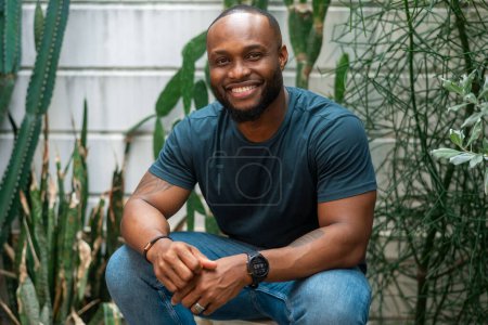 Téléchargez les photos : Heureux homme afro-américain souriant dans la cour arrière à la maison - en image libre de droit