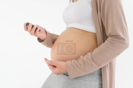 Pregnant woman checking blood sugar level by using Digital Glucose meter, health care, medicine, diabetes, glycemia concept
