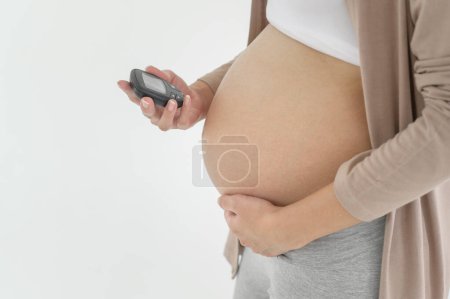 Femme enceinte vérifiant le taux de sucre dans le sang à l'aide de glucomètre numérique, soins de santé, médecine, diabète, concept de glycémie