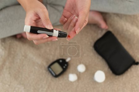 Téléchargez les photos : Gros plan de la femme vérifiant le taux de sucre dans le sang à l'aide de glucomètre numérique, soins de santé, médecine, diabète, concept de glycémie - en image libre de droit