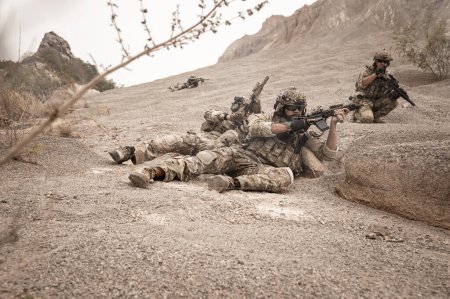 Soldiers in camouflage uniforms aiming with their rifle