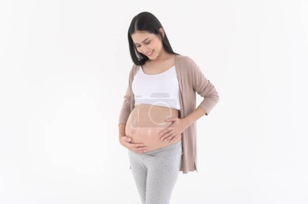 Téléchargez les photos : Belle femme enceinte appliquant hydratant, crème vergeture sur le ventre, traitement de fertilité infertilité, FIV, concept de maternité futur - en image libre de droit