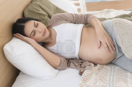 Téléchargez les photos : Femme enceinte dormant sur le lit, concept de grossesse et d'attente - en image libre de droit