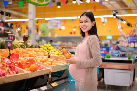 Téléchargez les photos : Belle femme enceinte faisant des achats d'aliments sains à l'épicerie - en image libre de droit
