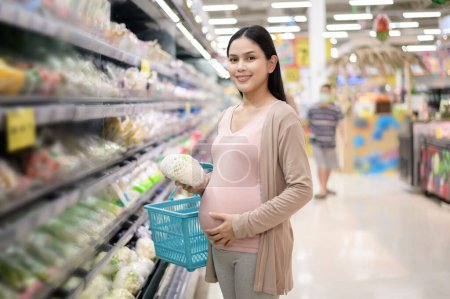 Téléchargez les photos : Belle femme enceinte faisant des achats d'aliments sains à l'épicerie - en image libre de droit