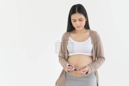 Téléchargez les photos : Femme enceinte vérifiant le taux de sucre dans le sang à l'aide de glucomètre numérique, soins de santé, médecine, diabète, concept de glycémie - en image libre de droit