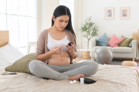 Téléchargez les photos : Femme enceinte vérifiant le taux de sucre dans le sang à l'aide de glucomètre numérique, soins de santé, médecine, diabète, concept de glycémie - en image libre de droit
