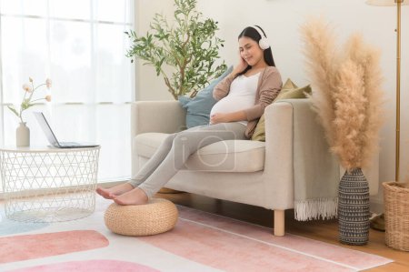 Mujer embarazada feliz con auriculares escuchando música mozart y acostado en el sofá, concepto de embarazo