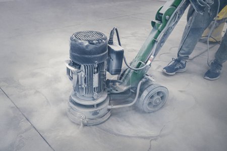 Foto de Sanding a concrete floor before painting with epoxy industrial paints - Imagen libre de derechos