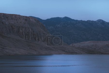Téléchargez les photos : Paysage nocturne dans les montagnes entourées de mer bleue, beau paysage, silhouettes de montagnes au crépuscule - en image libre de droit