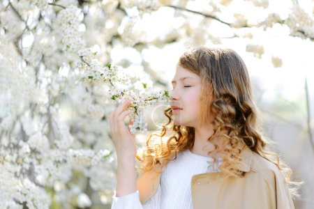 Foto de Beautiful teenager girl girl smelling flowers and enjoying warm sunny spring weather at the countryside - Imagen libre de derechos
