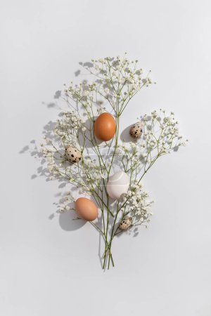 Téléchargez les photos : Aesthetic Easter composition, floral spring bouquet, natural color eggs on a light neutral background. Holiday greeting card design template - en image libre de droit