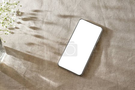 Téléchargez les photos : Modèle d'entreprise classique minimaliste, maquette de téléphone portable avec écran blanc sur un fond beige avec des ombres de soleil esthétiques - en image libre de droit