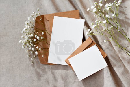 Téléchargez les photos : Modèle de marque de commerce floral esthétique, cartes en papier vierges et enveloppes sur un fond beige neutre, maquette avec espace de copie - en image libre de droit