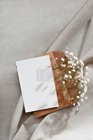 Foto de Tarjeta de papel en blanco y sobre con flores sobre un fondo beige neutro, plantilla de felicitación, invitación o tarjeta de felicitación con espacio de copia de maqueta - Imagen libre de derechos