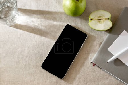 Photo for Mobile phone on a beige table with apples and sunlight shadows, business minimalist template - Royalty Free Image