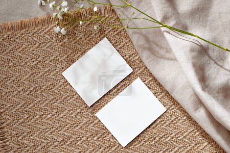 Téléchargez les photos : Deux cartes de feuille de papier vides et fleur sur un fond de tapis beige chaud, modèle d'affaires avec espace de copie maquette - en image libre de droit