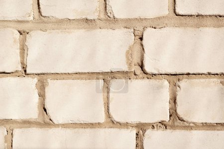 Foto de Una pared de ladrillo áspero torpe natural beige claro con textura de costuras de cemento desigual - Imagen libre de derechos
