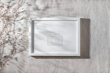 Téléchargez les photos : Modèle de cadre blanc horisontal sur un mur beige neutre avec des ombres de soleil florales esthétiques et de l'herbe séchée, affaires élégantes, gabarit de marque avec espace de copie - en image libre de droit