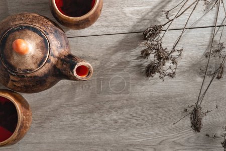 Téléchargez les photos : Authentique ensemble de thé céramique poterie sur un fond de table en bois avec fleurs sèches, concept de cérémonie du thé, théière artisanale et tasses, espace de copie - en image libre de droit