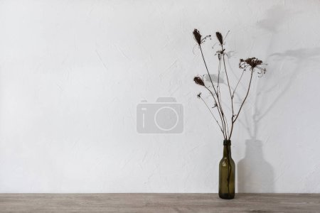 Foto de Plantilla de diseño interior minimalista de marca neutra, mesa de madera beige con flores secas en un jarrón, fondo de pared blanco vacío con sombras de luz solar floral, maqueta con espacio para copiar - Imagen libre de derechos