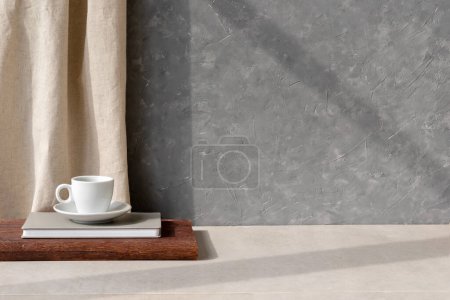 Téléchargez les photos : Fond moderne de design d'intérieur durable, mur en béton gris vide, table en pierre beige et rideau de lin, tasse à café sur un bureau en bois, ombres de soleil, gabarit neutre avec espace de copie - en image libre de droit