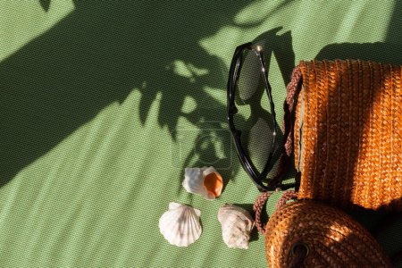 Foto de Relajación de verano, concepto de vacaciones, bolso de mujer, gafas de sol y conchas de mar en un fondo verde, blog de moda, plantilla de marca de negocios femeninos, espacio de copia - Imagen libre de derechos