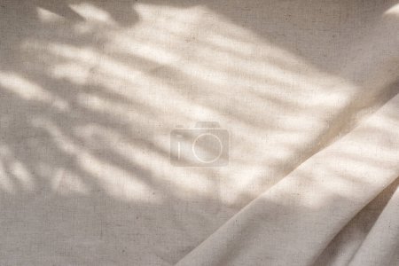 Foto de Textura de tela de lino beige con pliegues y sombras florales naturales de luz solar, fondo bohemio de boda de verano estético - Imagen libre de derechos