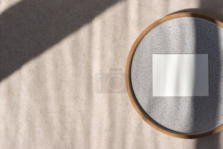 Foto de Tarjeta de papel en blanco maqueta en placa de cerámica gris en un mantel de lino beige neutro con sombras de luz solar geométrica, marca de negocio estética, plantilla de invitación de boda - Imagen libre de derechos