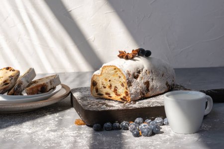 Foto de Estilo de vida desayuno de la mañana, pastel dulce en rodajas con pasas, taza de leche en una mesa con rayos de luz solar estéticos - Imagen libre de derechos