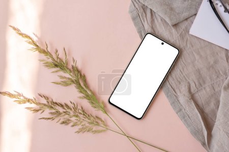 Photo for Aesthetic lifestyle business brand template, blank smartphone screen mock up, linen fabric, meadow grass on a light pink background, copy space - Royalty Free Image