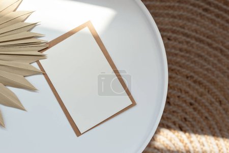 Photo for Minimalist elegant neutral business brand template, blank paper card with mockup copy space on a white table with dried grass and sunlight pattern, beige rug, lifestyle natural background, flat lay. - Royalty Free Image